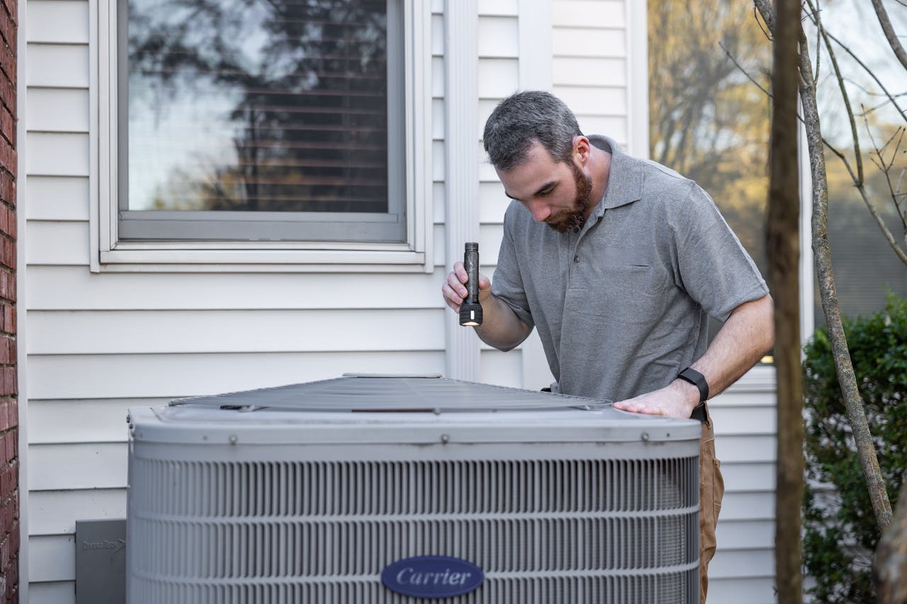A technician inspects an outdoor HVAC unit for maintenance.